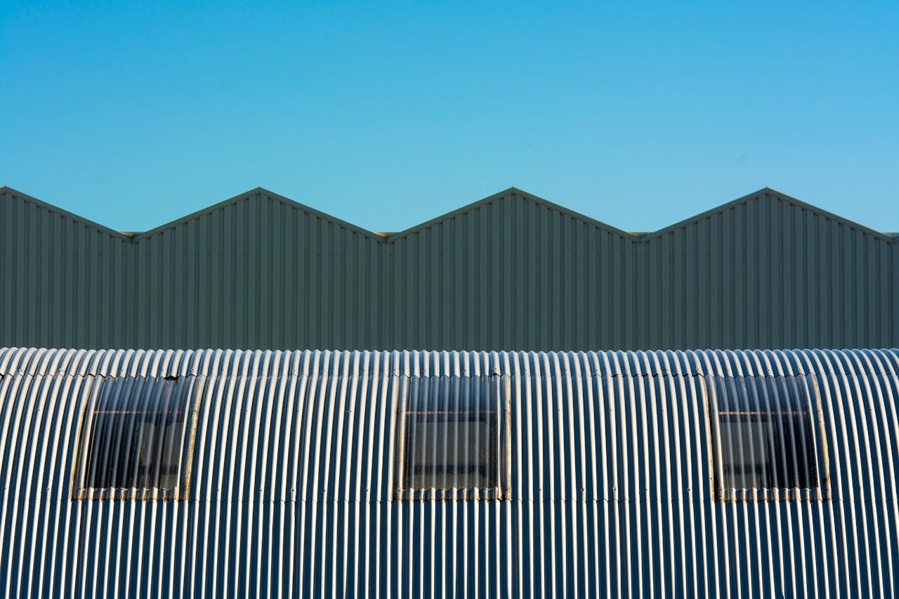 gallery-02 Industrial warehouse with corrugated and cylindrical roof design showcasing geometric structure.
