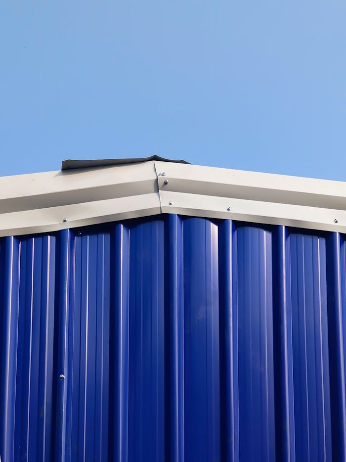 gallery-06 A detailed image of the roof edge of a blue metal building against a clear sky.