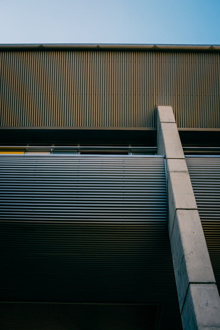 services-02 Low angle view of a contemporary building showcasing minimalist design and a corrugated metal facade.