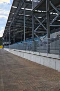 A metal grandstand at an outdoor racetrack during the day, showcasing industrial architecture.